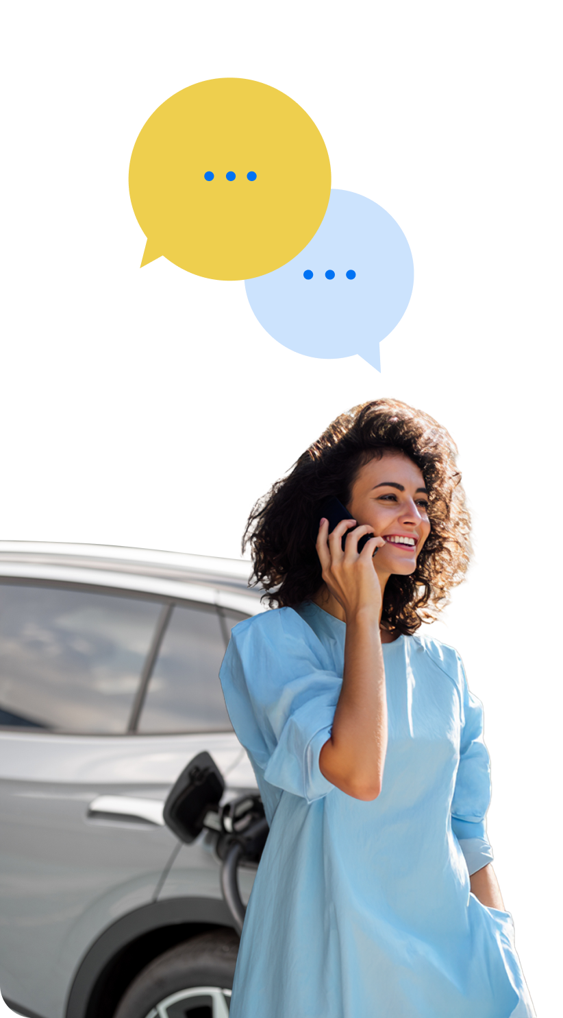 Mergina atsirėmusi į savo elektromobilį kalbasi telefonu.