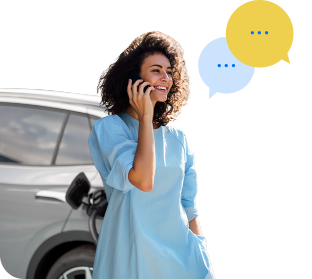 Mergina atsirėmusi į savo elektromobilį kalbasi telefonu.