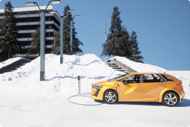 Snieguotą žiemą geltonas elektromobilis įsikrauna įkrovimo stotelėje.