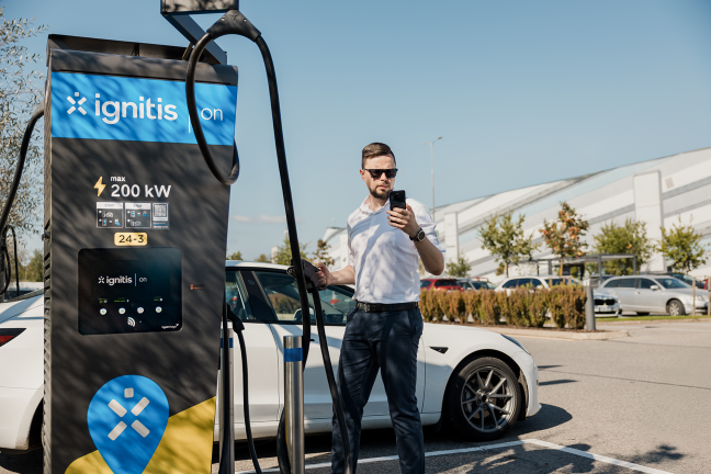 Verslininkas įsikrauna savo elektromobilį Ignitis ON itin greito įkrovimo stotelėje.