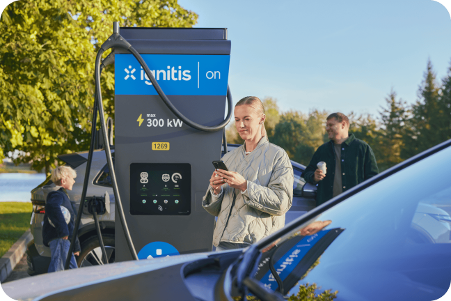 Moteris su savo šeima įsikrauna elektromobilį Ignitis ON itin greito įkrovimo stotelėje.